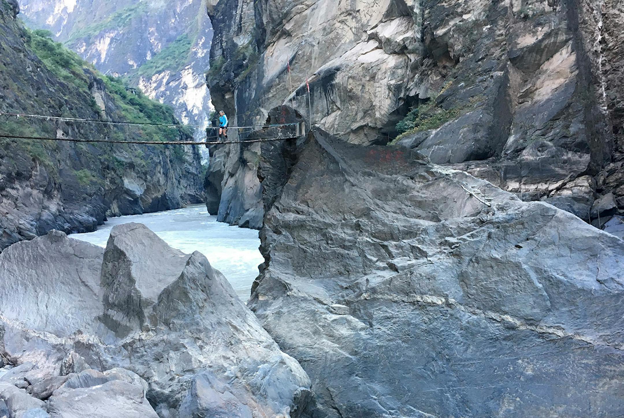 The author pays a small fee to walk across a primitive bridge leading to a rock in the middle of the Jinsha River, where a scenic view awaits.