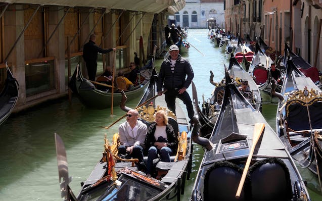 Tourists enjoy a ride on gondolas in Venice, Italy, Thursday, April 25, 2024.