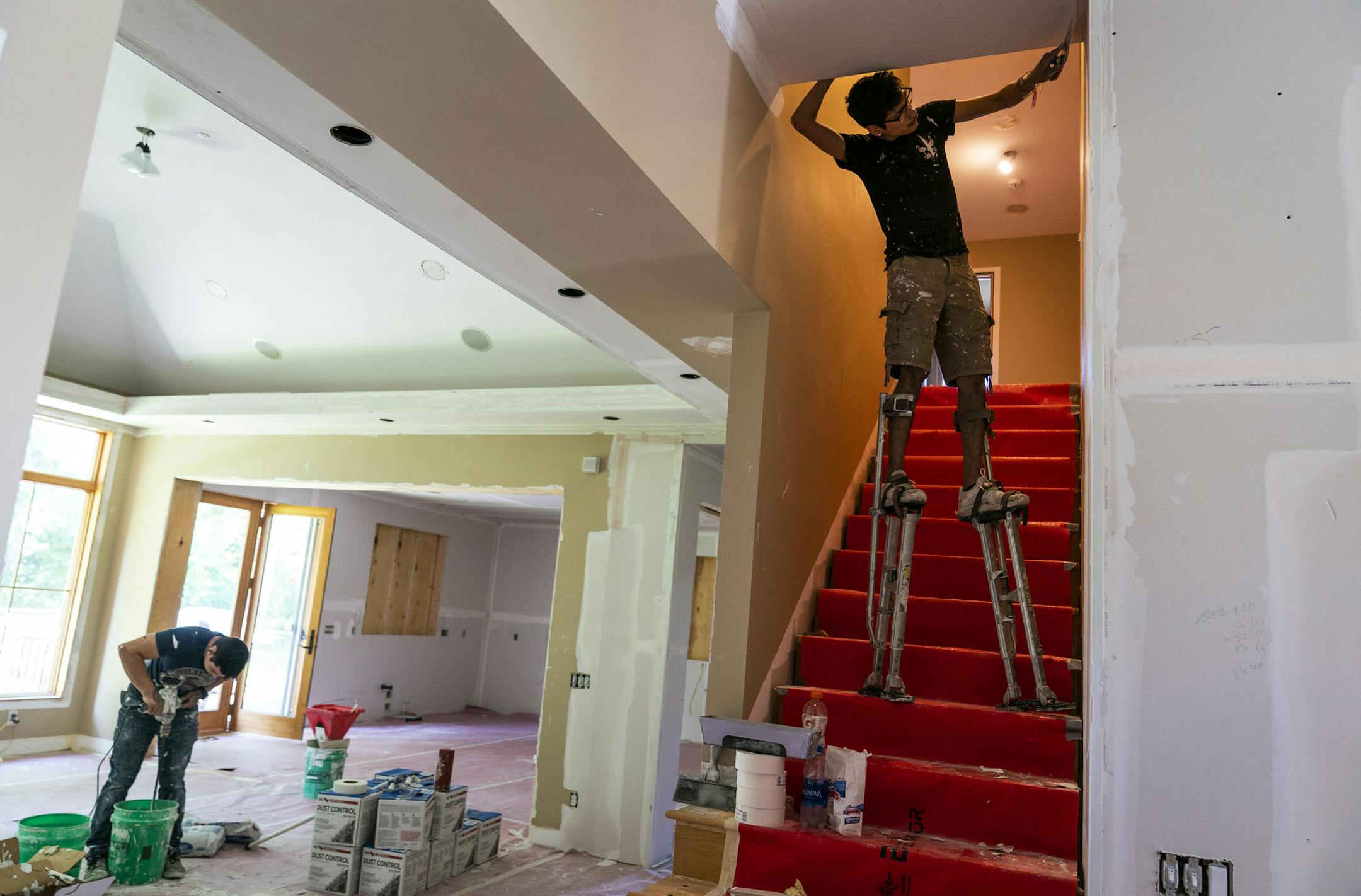 Jonathan Valverde, left, and Daniel Gomez of J&E Drywall LLC work on mudding the walls of Bronson's home during the remodel. ] LEILA NAVIDI • leila.navidi@startribune.com BACKGROUND INFORMATION: Remodeling work done on the home of Ray Bronson in Edina on Thursday, August 1, 2019.