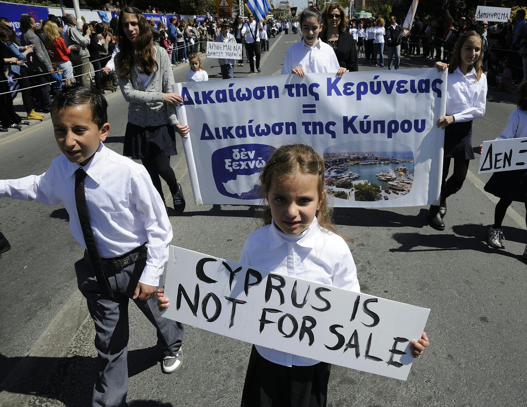 Students hold placards the ones on the right reads in Greek "we don't sell out "during a parade for Greek independence day celebrations at the southern port city of Limassol, Cyprus,Monday, March 25, 2013. Cyprus secured what its politicians described as a ìpainfulî solution to avert imminent bankruptcy, agreeing early Monday to slash its oversize banking sector and make large account holders take losses to help pay to secure a last-minute euro10 billion (US$13 billion) bailout. (AP Ph