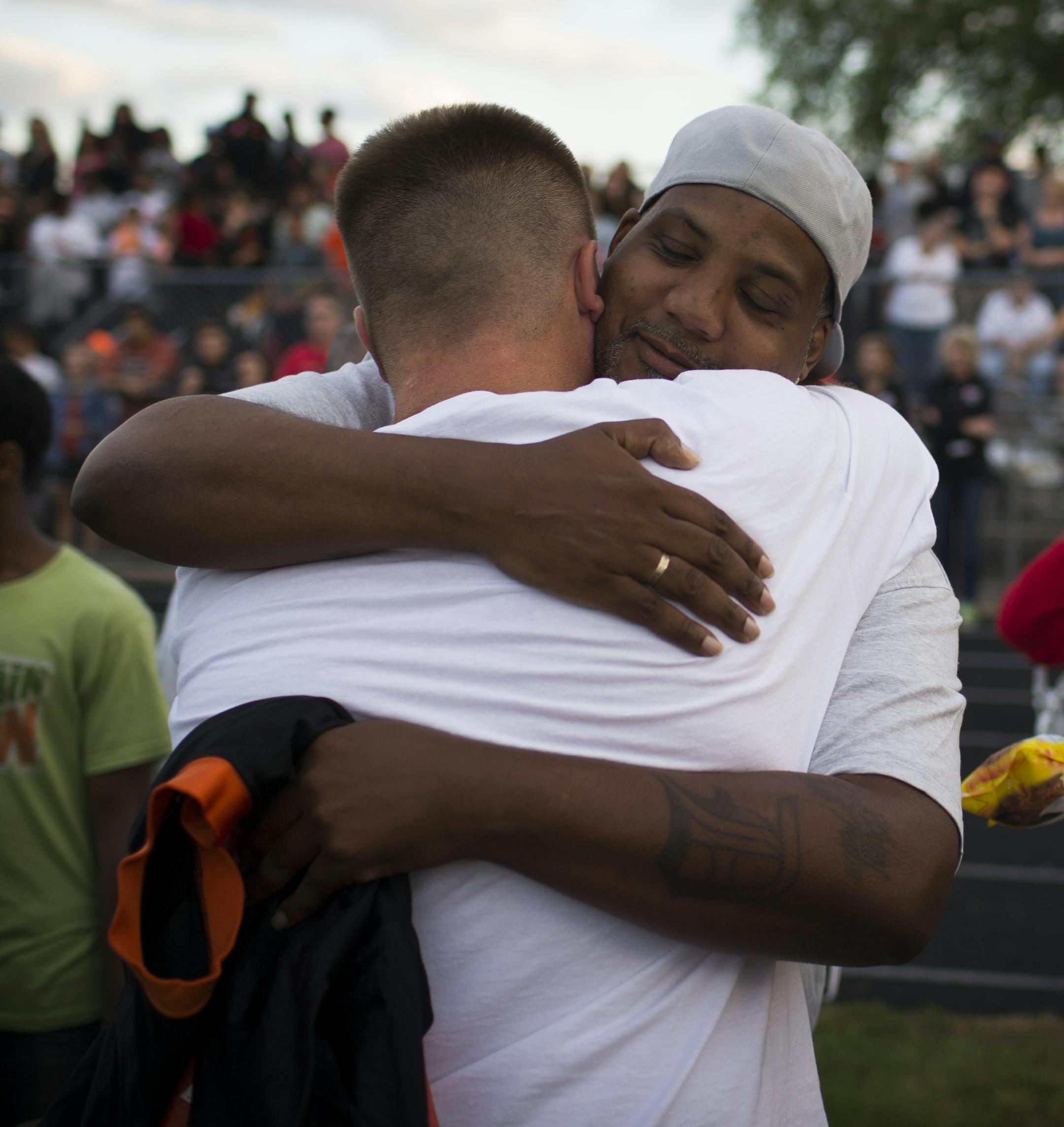 Sha-kym Adam's father Sharrod Rowe hugged South head coach Lenny Sedlock as his mother Kimberly Adams, right, cried while holding his jersey during a memorial time for Sha-kym at the first football game of the season at South High School in Minneapolis, Minn. August 27, 2014. Adams was a football player and died earlier this month in a drowning accident. ] RENEE JONES SCHNEIDER • reneejones@startribune.com
