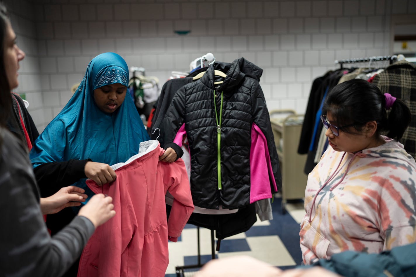 Eleventh grader Caisha Hassan and twelfth grader Anna Wagner restock some clothing items like winter coats at the Eagle Nation Station, a free pantry offering food, school supplies, personal hygiene items, clothing and even household items like laundry detergent to students in need, at Eden Prairie High School on Tuesday, Dec. 19, 2023 in Eden Prairie, Minn. ] RENEE JONES SCHNEIDER • renee.jones@startribune.com