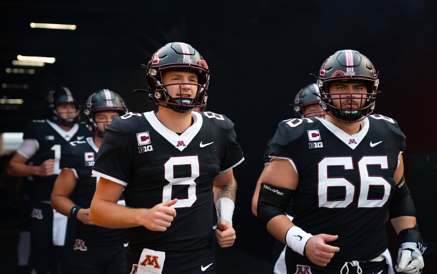 Gophers quarterback Athan Kaliakmanis (8) and offensive lineman Nathan Boe (66) run out of the tunnel for warmups Saturday