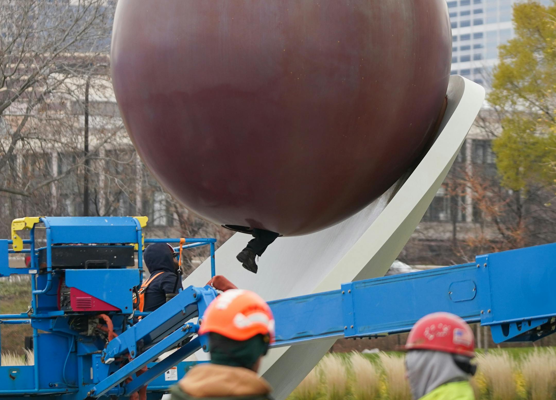 The 17500 pound aluminum cherry ball is unbolted, lifted, and separated from the Spoonbridge base it sits atop at the Sculpture Garden in Minneapolis, Minn., on Tuesday, Nov. 16, 2021. Due to the typically harsh conditions of Minnesota winters, this iconic Minneapolis fruit requires a fresh coat of paint about every ten years to keep the cherry's red crisp and glossy. The foot of Leon Budke, an employee with Rocket Crane Services, is seen as he climbs up inside the cherry to remove the bolts that keep it in place on the spoon. ] SHARI L. GROSS • shari.gross@startribune.com