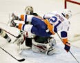 New York Islanders right wing Kyle Okposo (21) goes airborne as he skates in on Minnesota Wild goalie Niklas Backstrom (32), of Finland, during the th