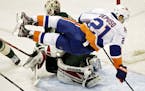 New York Islanders right wing Kyle Okposo (21) goes airborne as he skates in on Minnesota Wild goalie Niklas Backstrom (32), of Finland, during the th