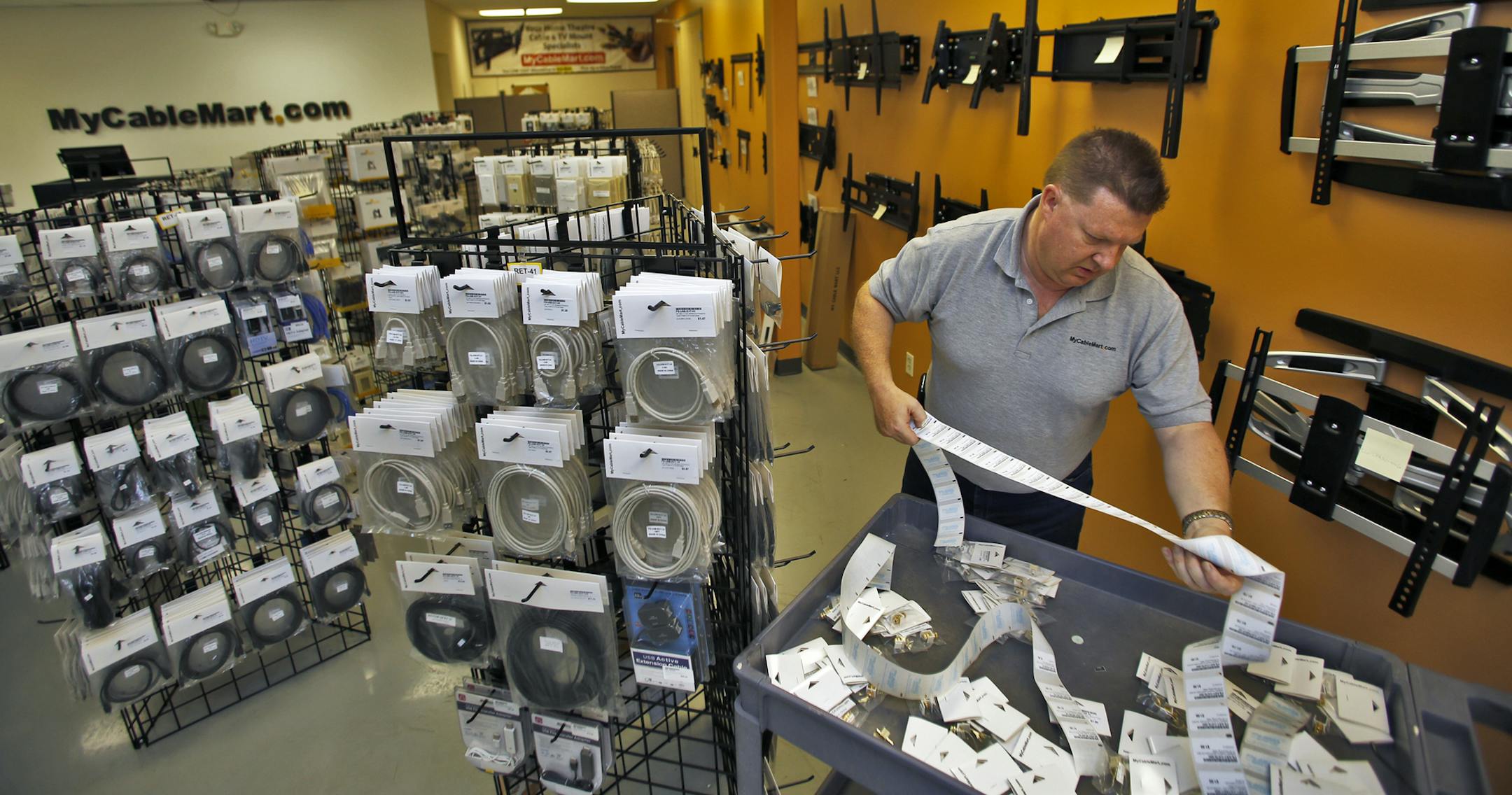 Mycablemart.com, an Eden Prairie-based online retailer, just opened its first retail store next to its new warehouse. Neil Marriott, CEO and owner, worked on logging inventory for the retail store. At right is a wall display of TV mounts. . (MARLIN LEVISON/STARTRIBUNE(mlevison@startribune.com)