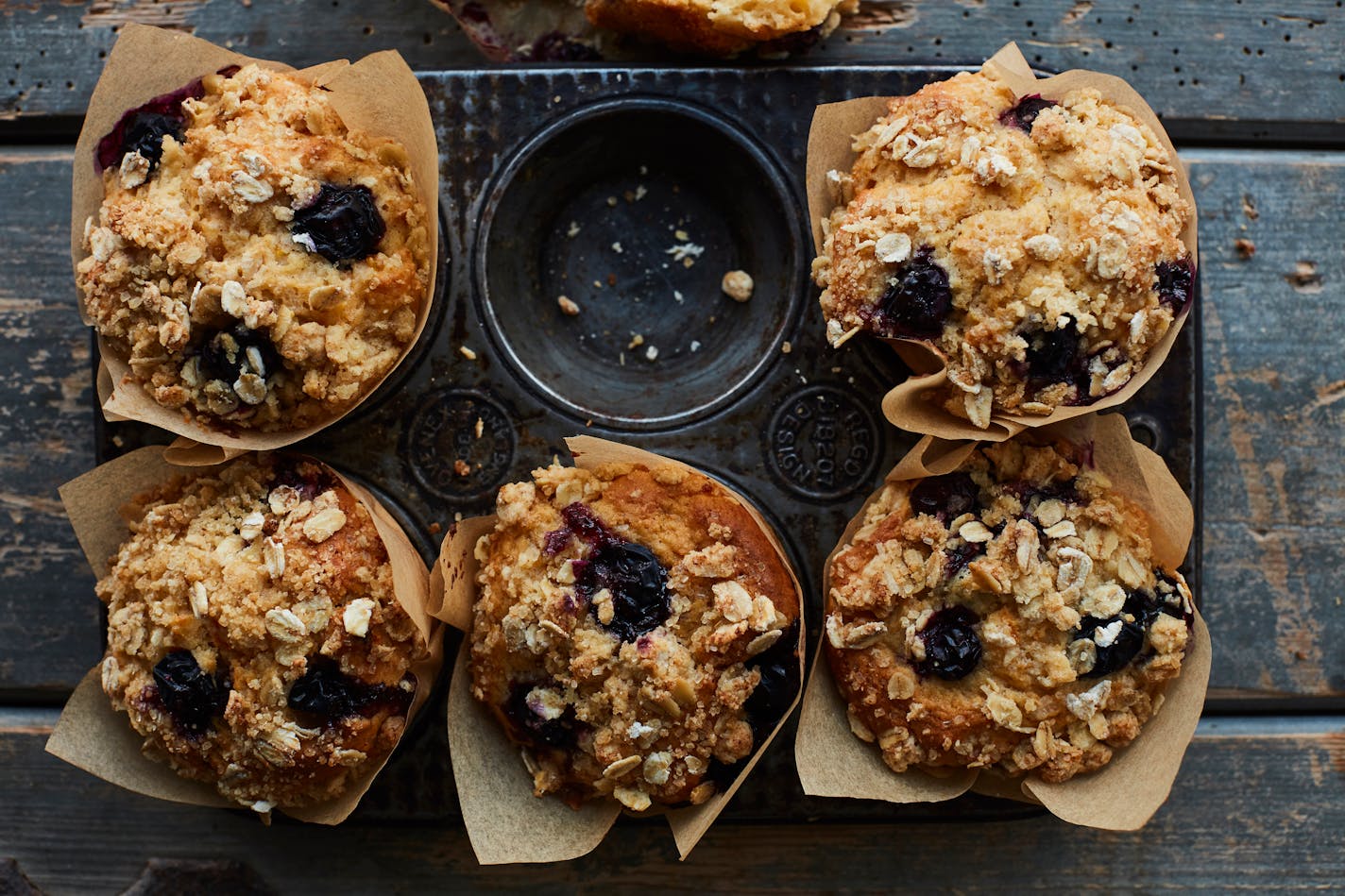 A tin of six vegan apricot, apple and blueberry muffins with crumble on top.