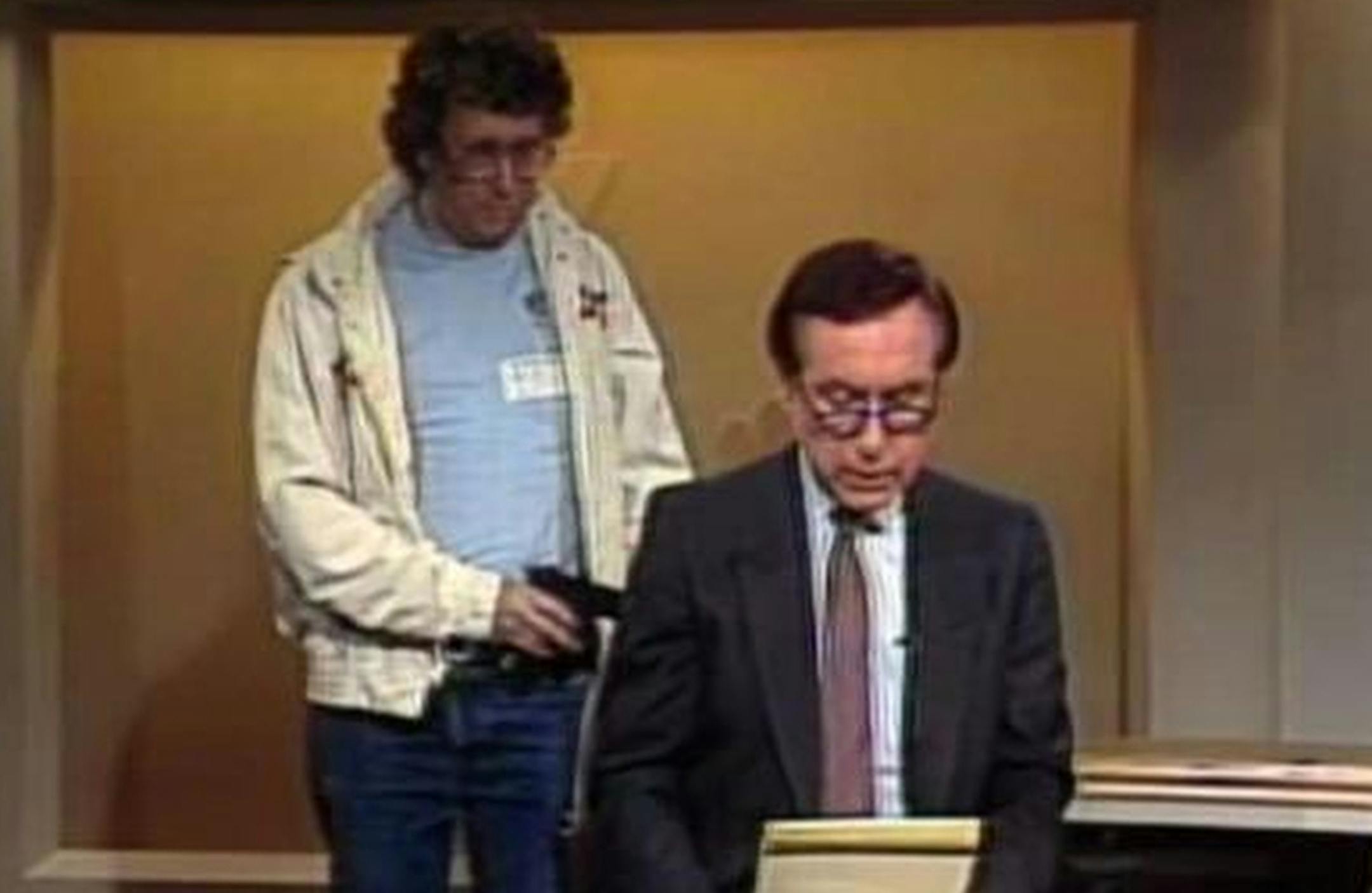 This Aug. 20, 1987, image made from video shows an intruder with a gun, as journalist David Horowitz is taken hostage during a live broadcast of Channel 4 Los Angeles. Horowitz remained calm and read the gunman's statements on camera, but the station had cut the broadcast without the gunman becoming aware of that fact. The gun turned out to be a toy BB gun, and Horowitz then took on the campaign to ban toy guns that look like real guns. Longtime consumer journalist David Horowitz has died at age