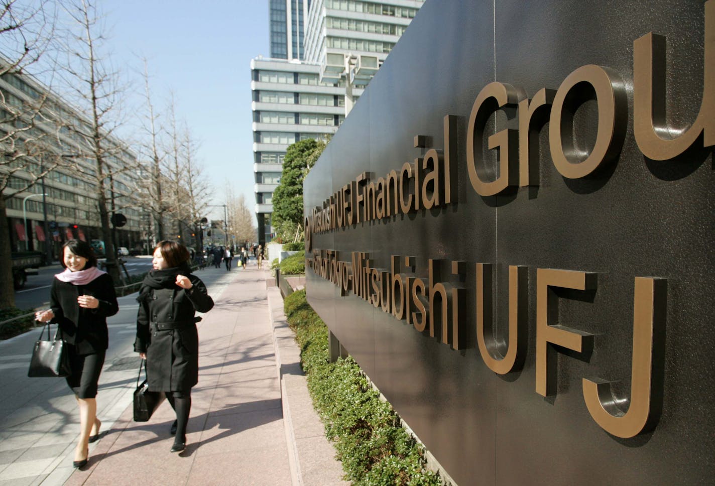 Japanese women walk past Bank of Mitsubishi UFJ Financial Group and Tokyo-Mitsubishi UFJ headquarters in Tokyo Monday, Feb. 13, 2006. A Japanese court on Monday rejected Sumitomo Trust &amp; Banking Co.'s suit against UFJ Holdings Inc. for scuttling a planned alliance and merging with another company Mitsubishi Tokyo Financial Group Inc. Sumitomo Trust had demanded 100 billion yen (US$850 million; euro710.11 million) in compensation from UFJ. But Tokyo District Court turned that down, a court official said on condition of anonymity, citing court rules. The Mitsubishi-UFJ merger, finalized earlier this year, created the Bank of Tokyo-Mitsubishi UFJ. The bank opened Jan. 4 as the world's largest financial group by assets, at around 190 trillion yen, or US$1.6 trillion (euro1.34 trillion). (AP Photo/Shizuo Kambayashi)