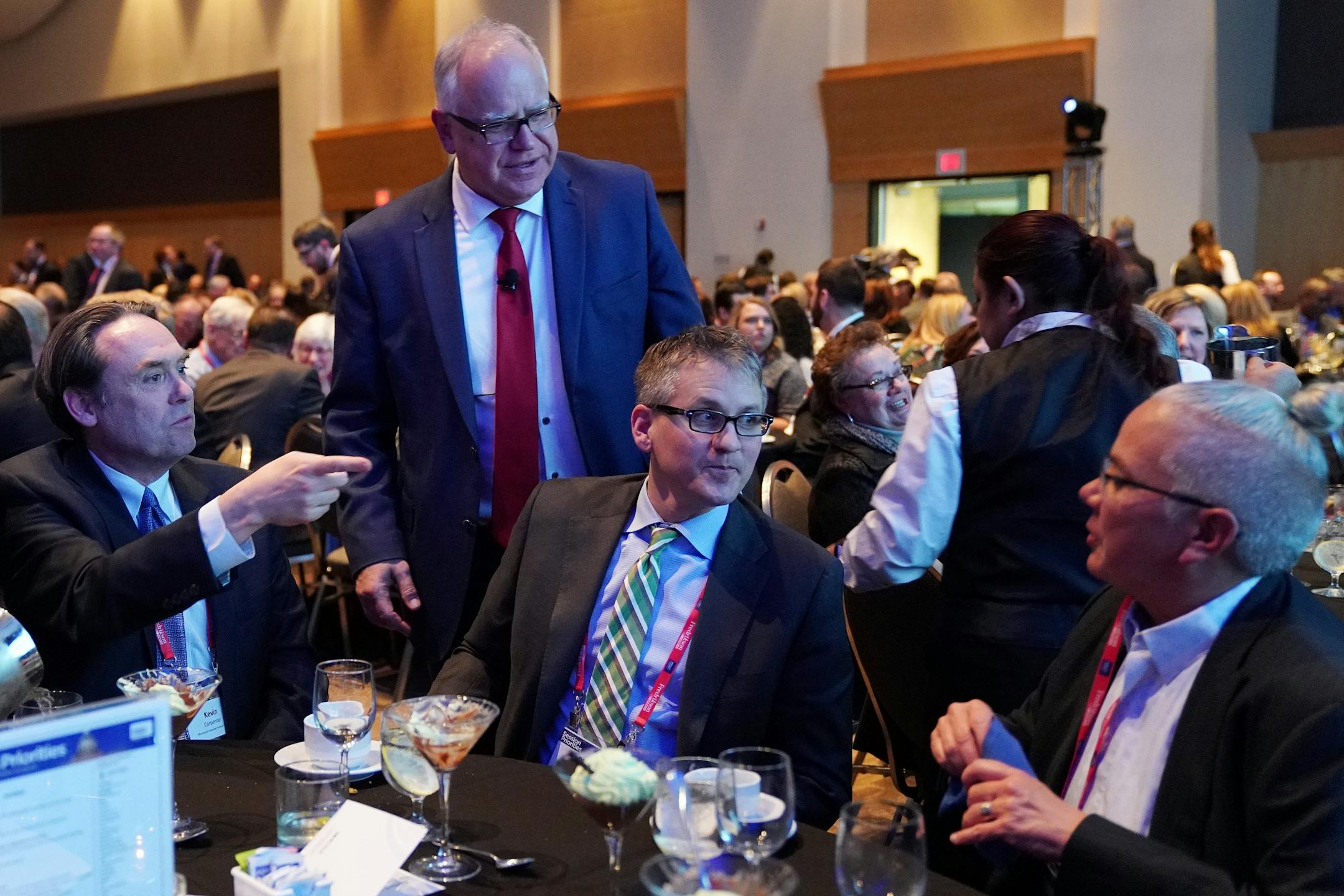 Gov. Tim Walz stopped by the table of his Commissioner of the Minnesota Housing Finance Agency Jennifer Ho, right, during the Minnesota Chamber of Commerce's annual policy kickoff event Wednesday.