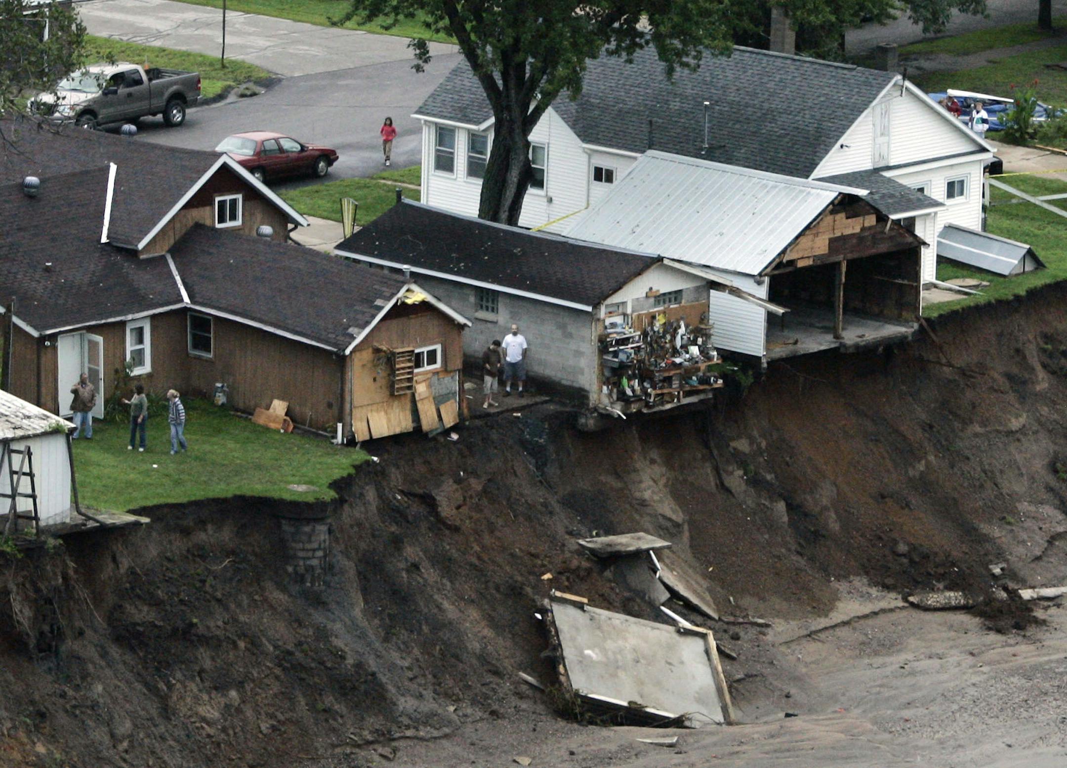 Houses and buildings protrude over the edge where flood waters caused the earth to give away north west of Winona, Minn., Monday, Aug. 20, 2007. Floodwaters from the severe storms that deluged parts of the Midwest with as much as a foot of rain over the weekend killed six people in southeastern Minnesota. (AP Photo/Jim Mone) ORG XMIT: MNJM105 ORG XMIT: MIN2014091217055983