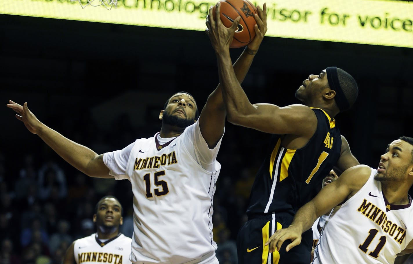 Maurice Walker(15) defends against Iowa's Melsahn Basabe (1) as Joe Coleman(11) bodies him on Sunday at Williams Arena.