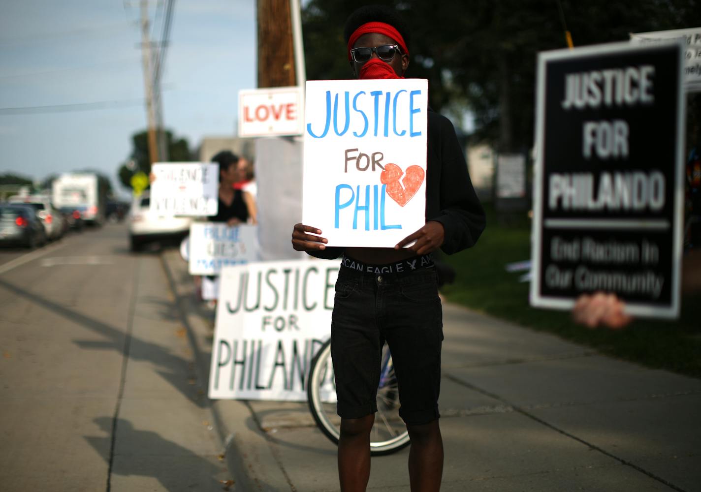 Demonstrators, including Emmanuel Kandolo, foreground held signs as they took part in the vigil along a busy Larpenteur Ave. ] JEFF WHEELER &#xef; jeff.wheeler@startribune.com A vigil for Philando Castile took place Monday evening, August 29, 2016 outside the Minnesota State Fair. Two groups, Merriam Park Neighbors for Peace and St. Paul Eastside Neighbors for Peace, gathered at the site on Larpenteur Ave. near Snelling Ave. where Castile was fatally shot by a St. Anthony police officer in July.