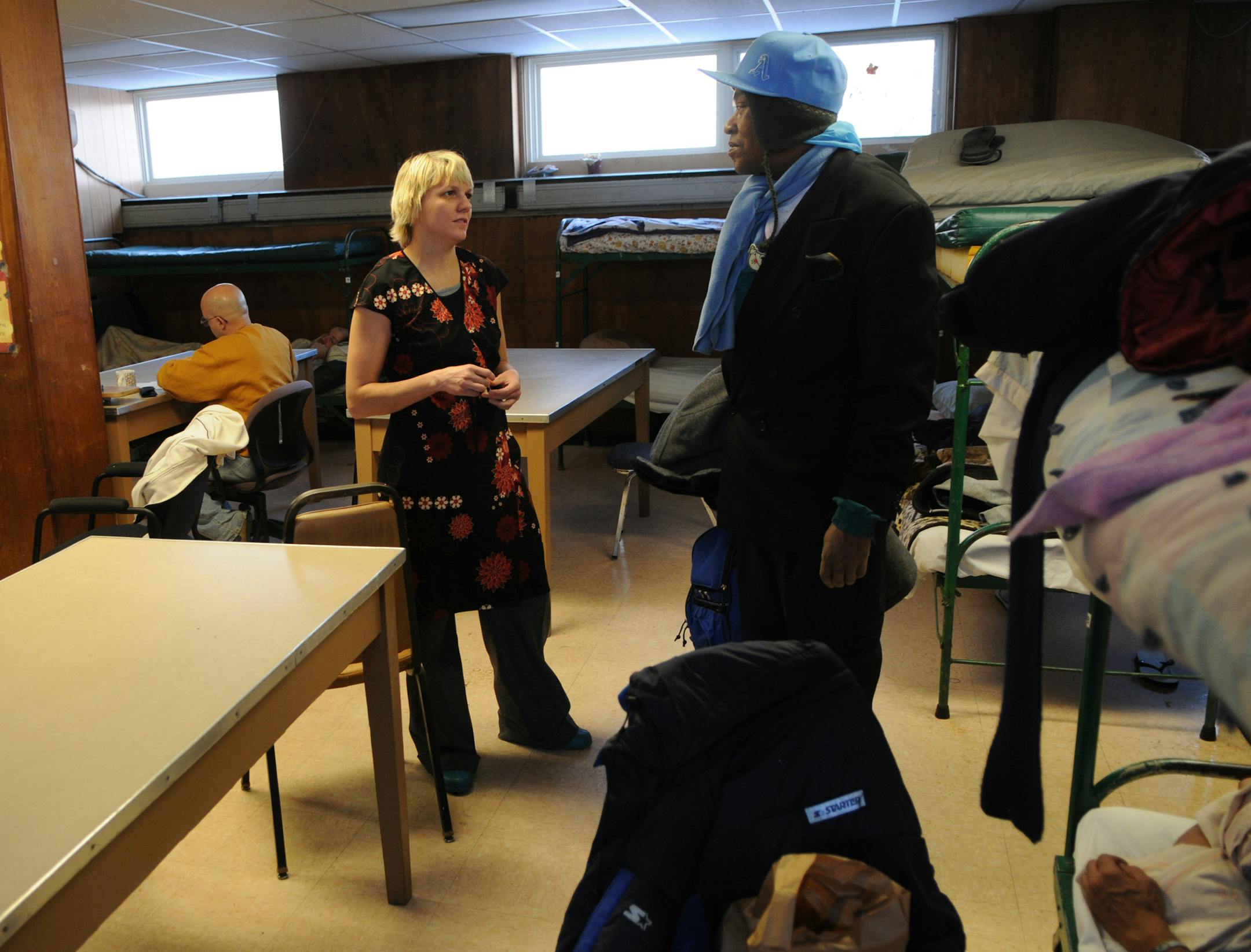 Shelter director Allysen Hoberg catches up with a client before a Monday night bed lottery.