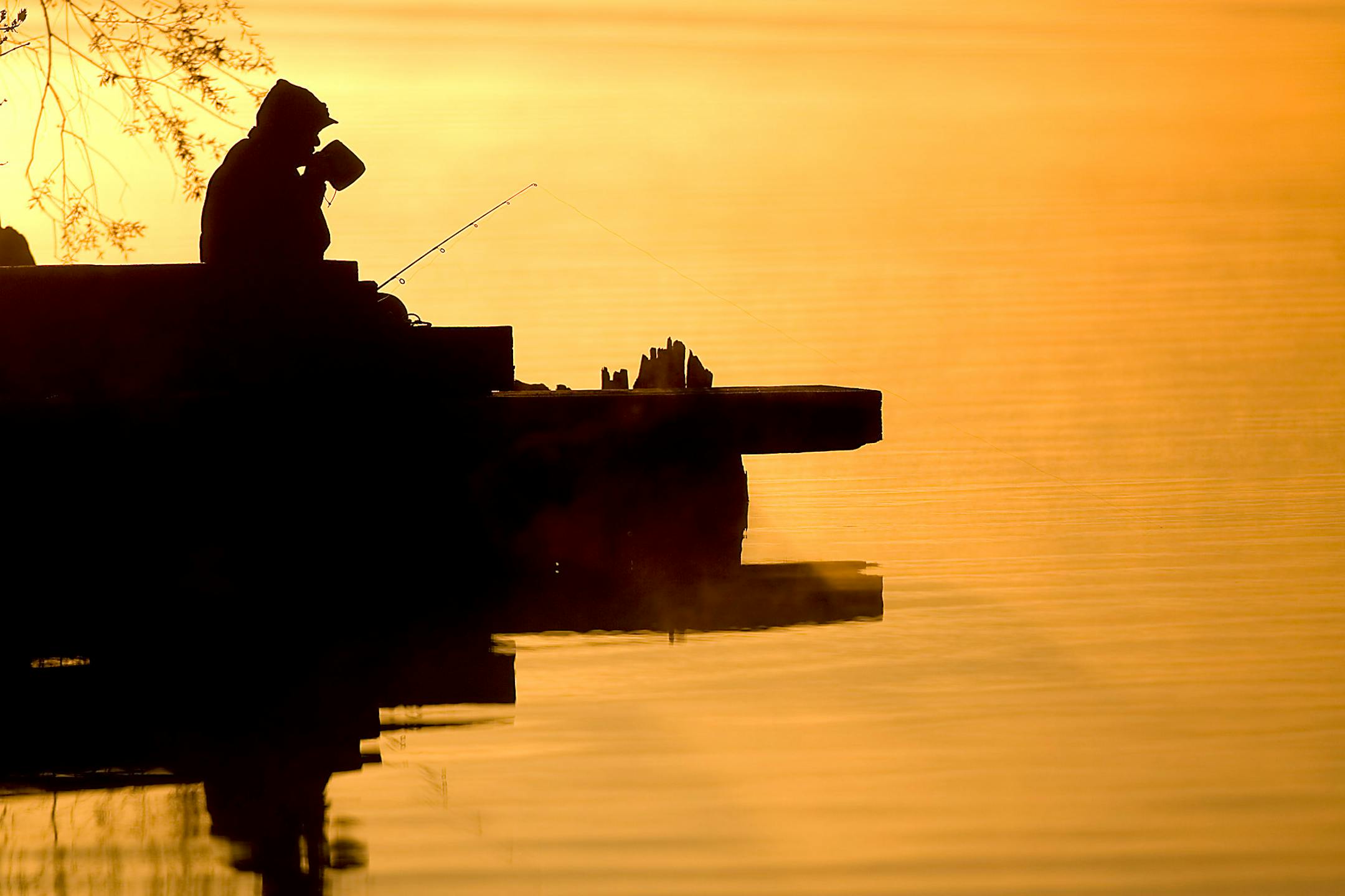 An angler sips coffee as he fishes on the St. Louis River at the Spirit Lake Marina near Duluth, Minn.