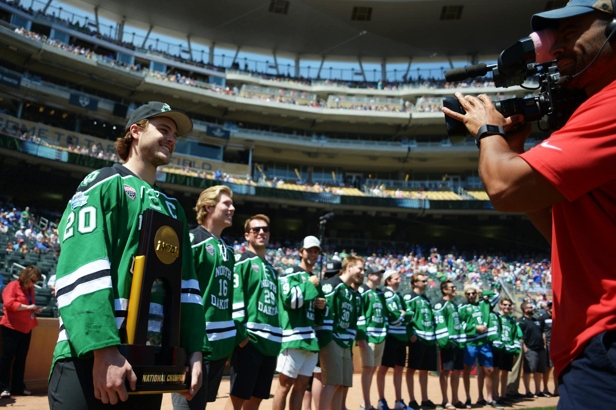 Gage Ausmus, of East Grand Forks, Minn., wore a proud smile and his University of North Dakota jersey in the back yard of the Minnesota Gophers at Target Field in Minneapolis. UND was honored for winning the NCAA hockey championship.