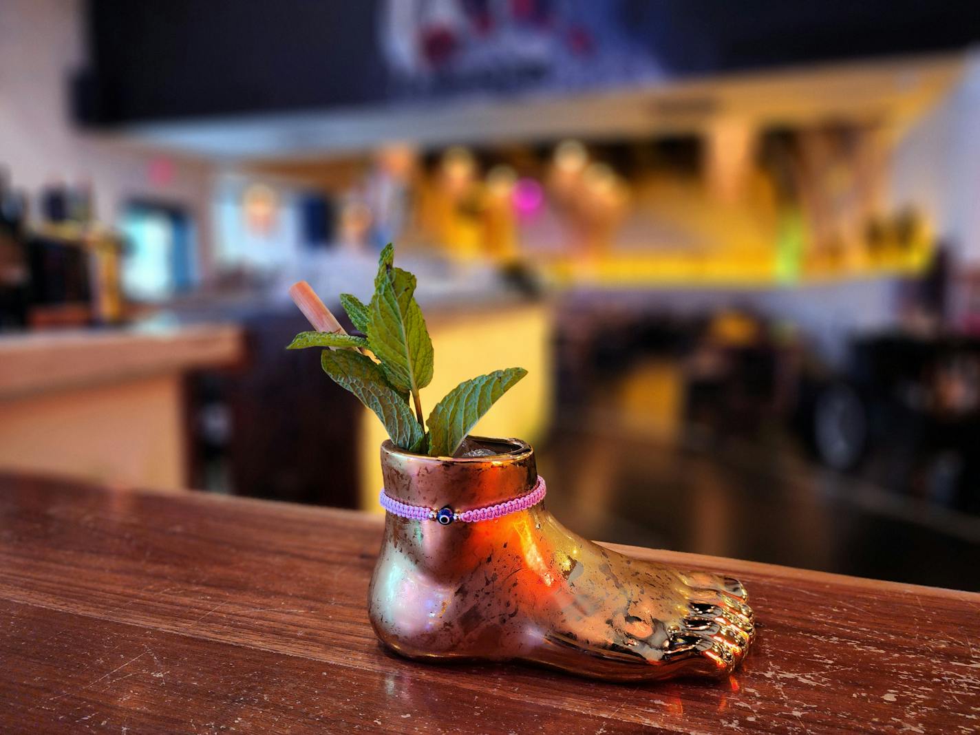 A bronze foot-shaped glass with a sprig of herbs poking out