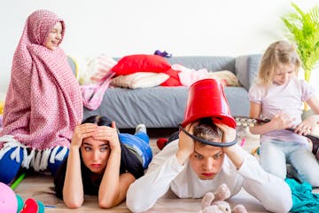 Tired parents lying on floor and their romping kids