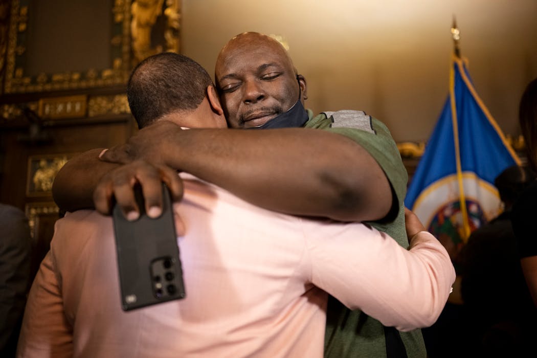 Andre Locke Sr., left, father of Amir Locke, and Amir’s uncle Andrew Tyler shared an embrace after the bill signing. Amir Locke was fatally shot by Minneapolis police.