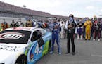 Driver Bubba Wallace, front left, and team owner Richard Petty, front right, stand for the National Anthem in the pits of the Talladega Superspeedway 