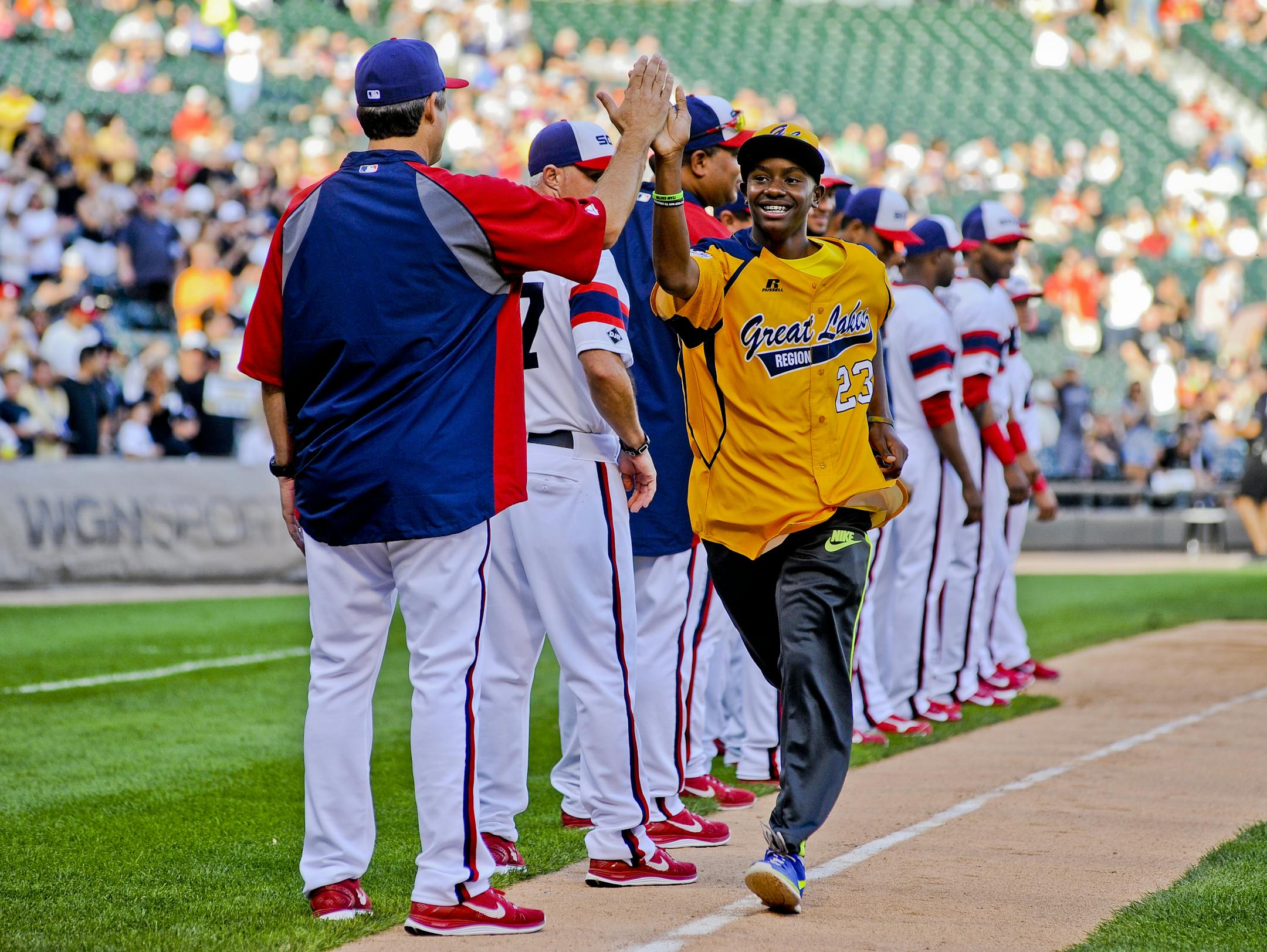 A member of the Jackie Robinson West Little League team high-fives a member of the Chicago White Sox as they were honored before the second game of the White Sox's baseball doubleheader against the Detroit Tigers in Chicago on Saturday, Aug. 30, 2014. (AP Photo/Matt Marton)