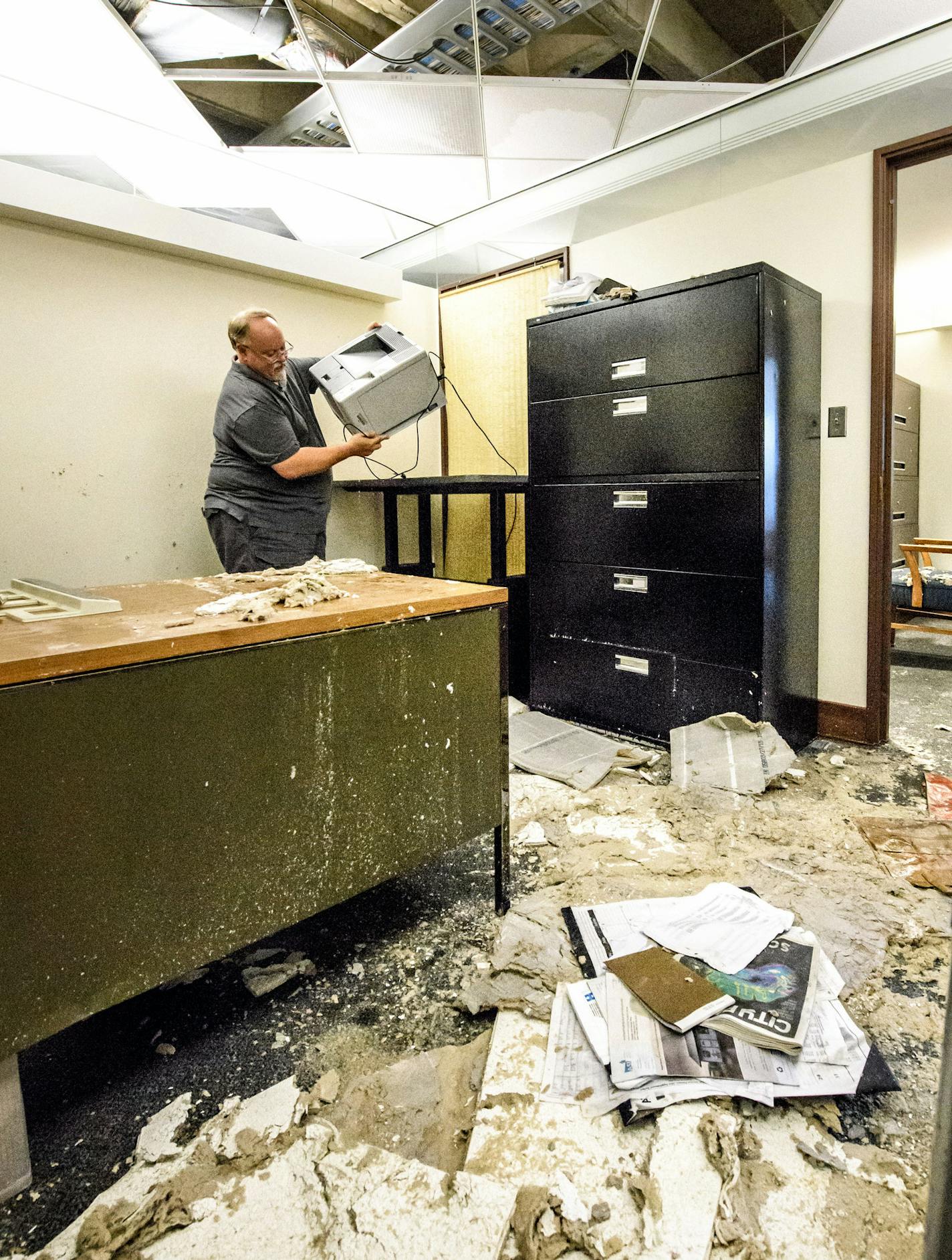 Fiscal Analyst Doug Berg carried a wet printer from his flooded office on the third floor of the State Office Building at the State Capitol. The ceiling tiles had fallen down. ] GLEN STUBBE * gstubbe@startribune.com Thursday, July 7, 2016 228799 Water valve broke in the State Office Building, which houses lawmakers and staff. Building was already in need of some work.