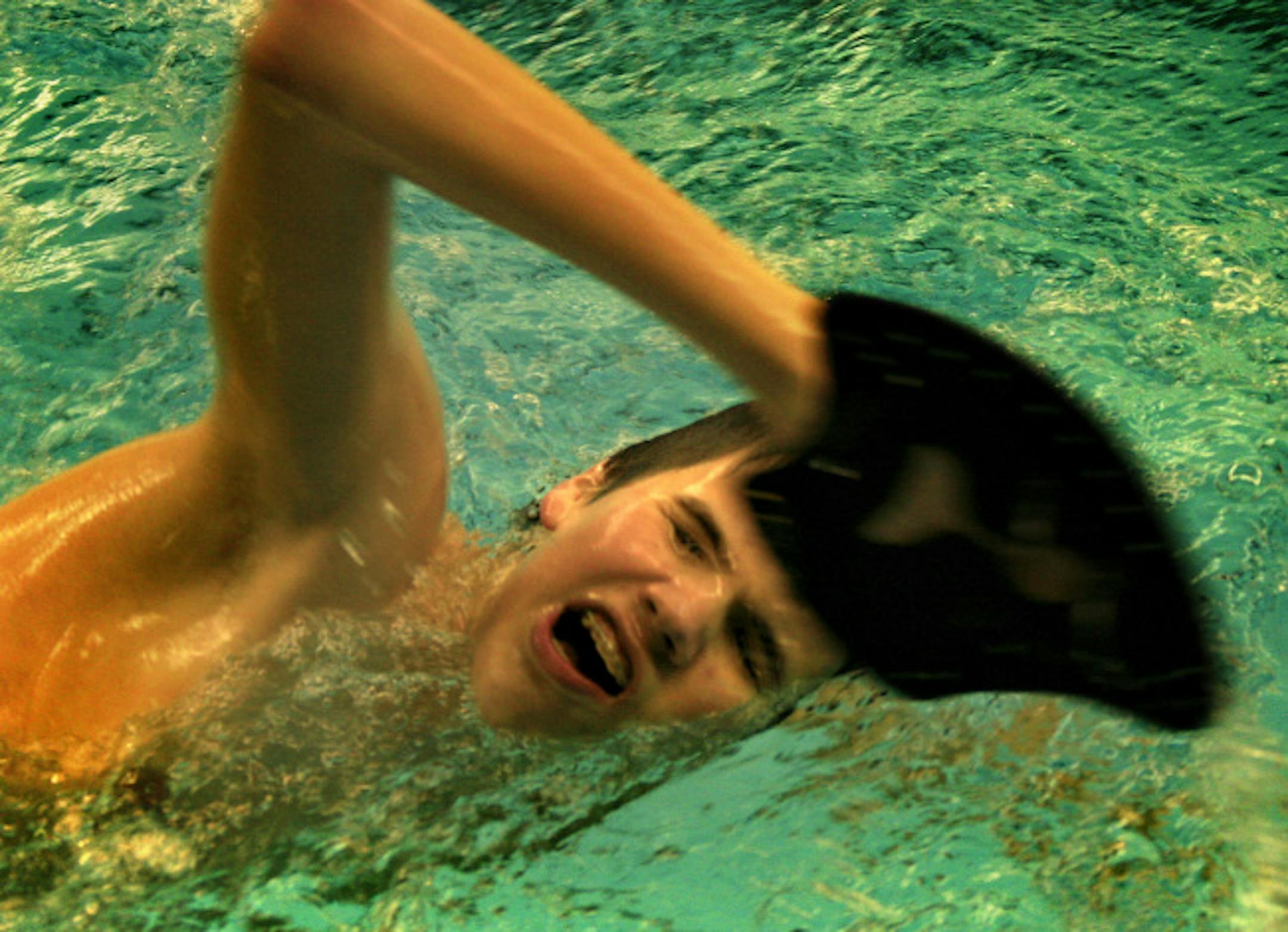 Kelby Carlson, a blind swimmer, is on Woodbury's junior varsity team. He is shown practicing at Edina's Southview pool where his mom coaches the Edina team. He is using paddles on his hands to help improve his swimming technique.