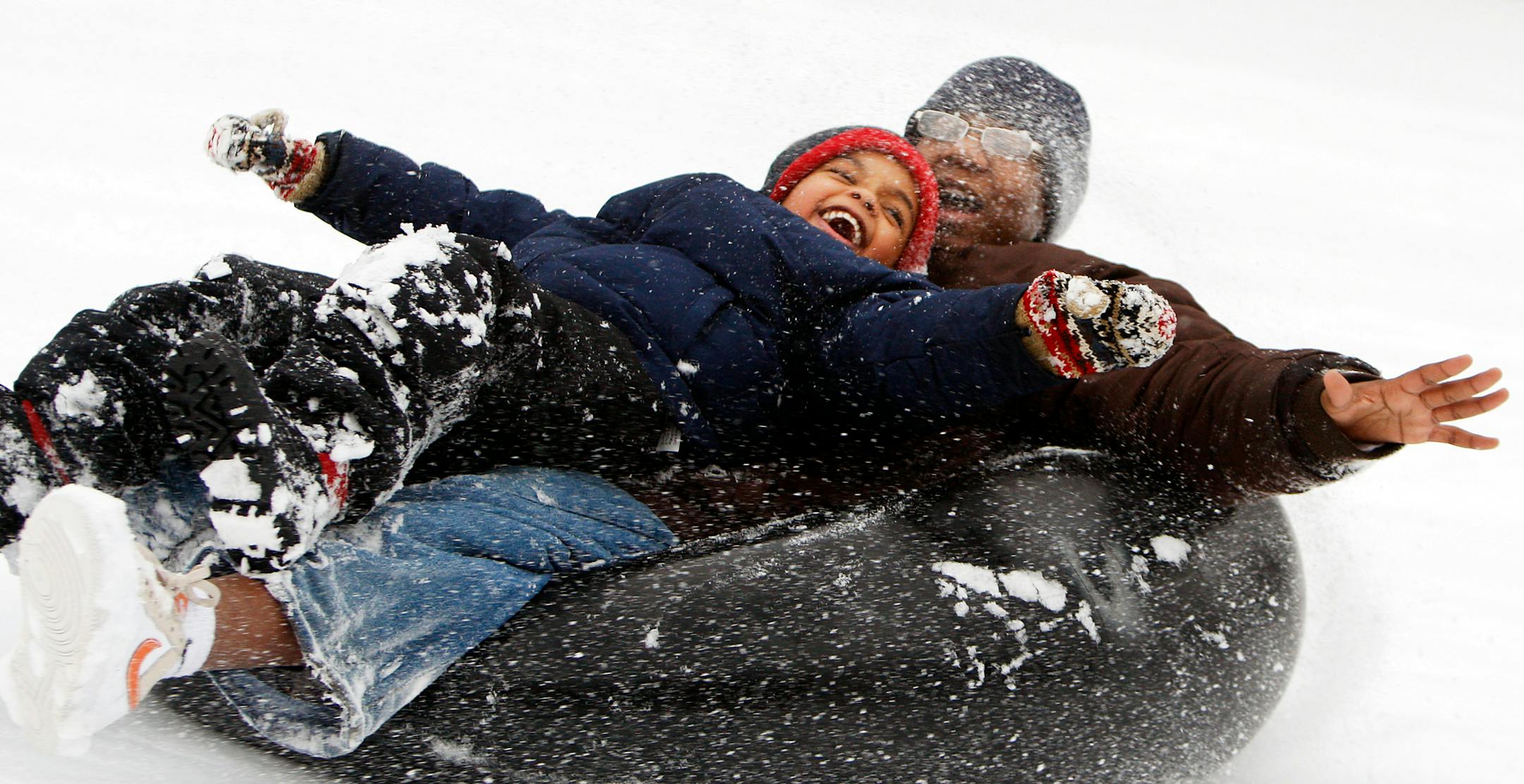 Friends Christian Abraham, 5, and Miles Ware Jr., 14, engaged in a little slipping and sliding for fun at Theodore Wirth Park after school on Monday. They brought the inner tube, and Monday's snow freshened up a hill on the golf course.