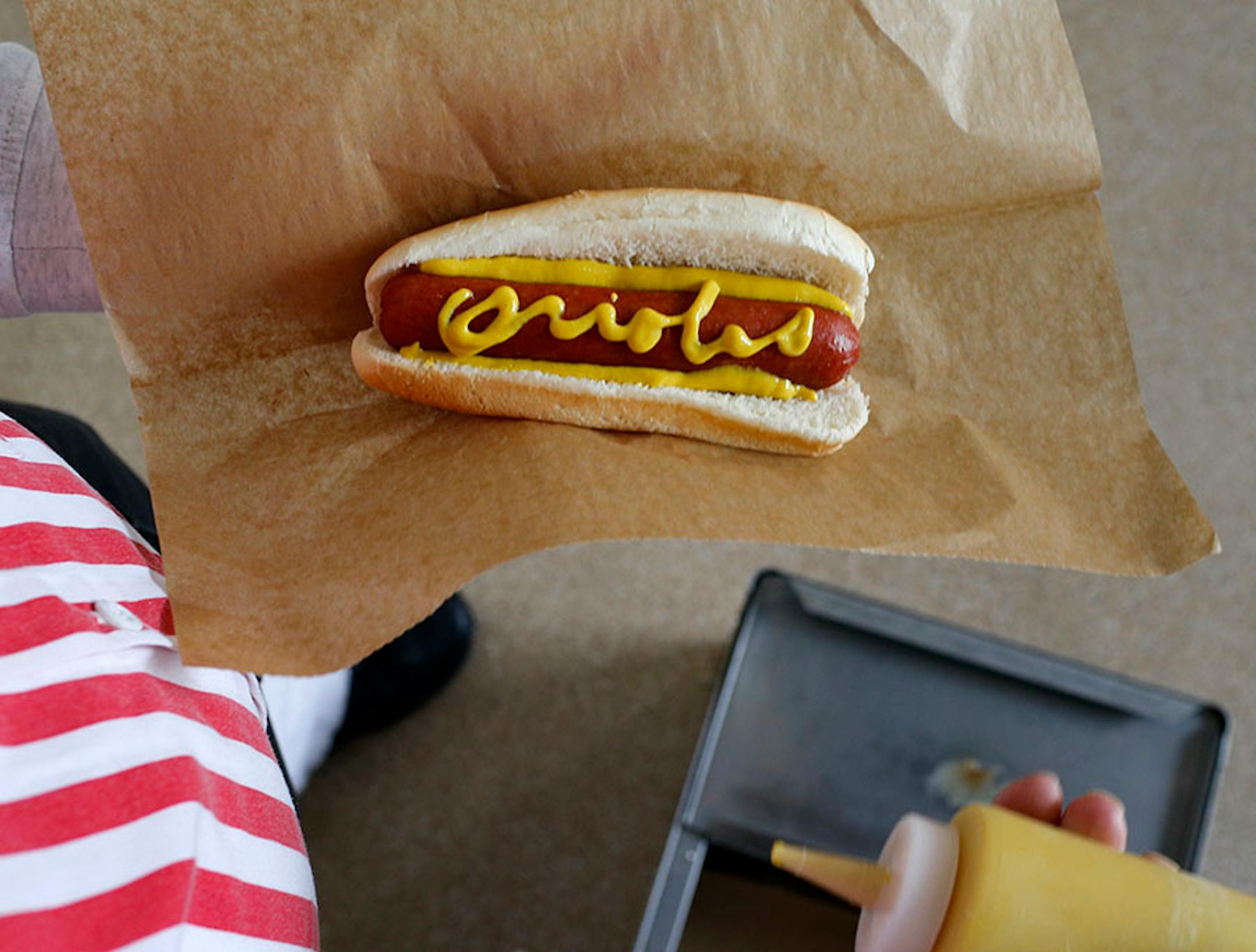 A vendor displays a hot dog with "Orioles" written in mustard before an opening day baseball game between the Baltimore Orioles and the Minnesota Twins in Baltimore, Monday, April 4, 2016. (AP Photo/Patrick Semansky)