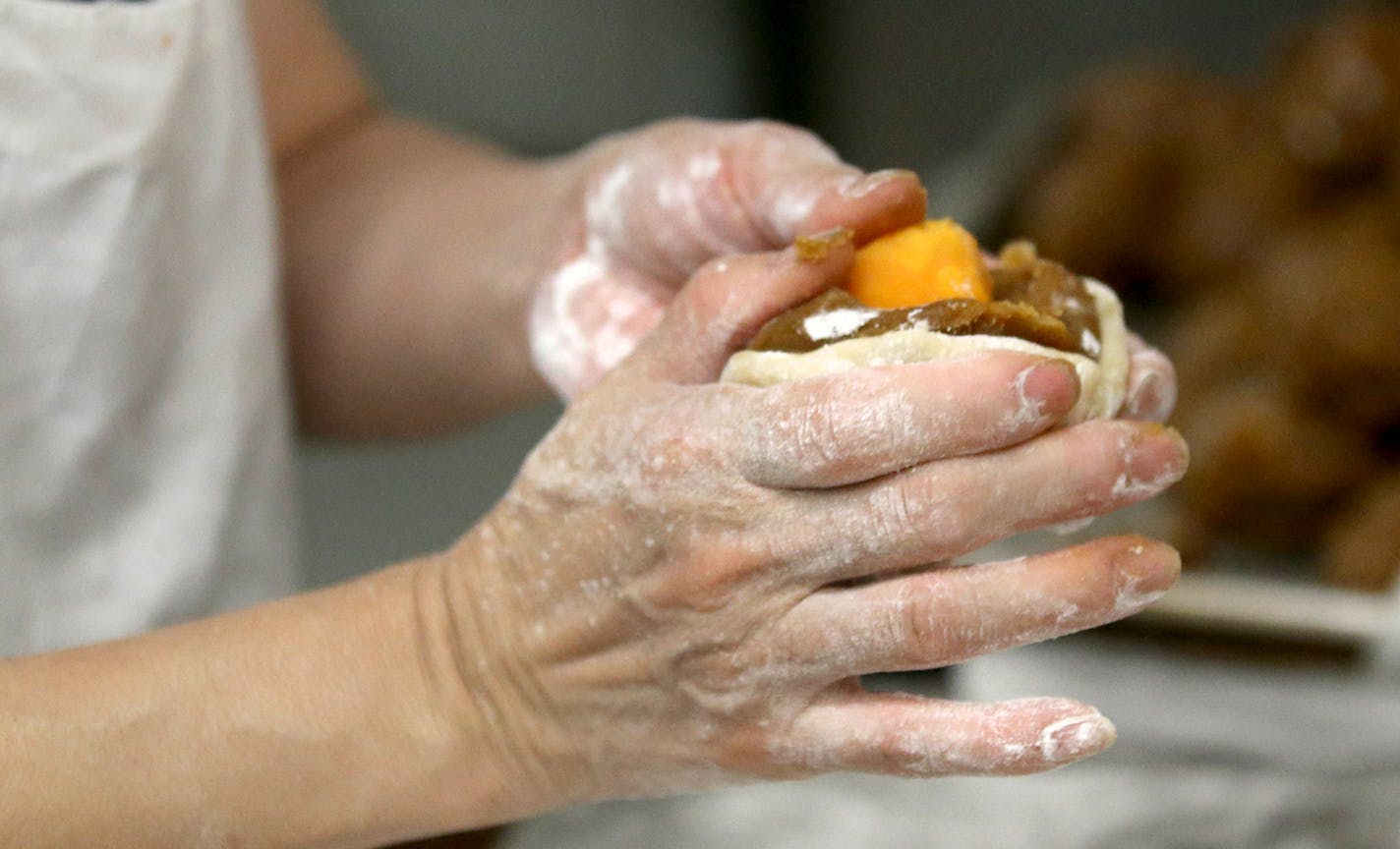 Pauline Kwan made mooncakes ahead of the lunar calendar harvest holiday that begins on Monday. Mooncakes are a specialty at the Mid-Autumn Festival and this is one of the only places in the Twin Cities where they are made. Here, Kwan, who has been making mooncakes for 35 years, fashions dough around an egg yolk and filling before placing in a wooden mold to form a moonlike before baking and seen Wednesday, Sept. 18, 2018, in Minneapolis, MN.] DAVID JOLES &#xef; david.joles@startribune.com Michel