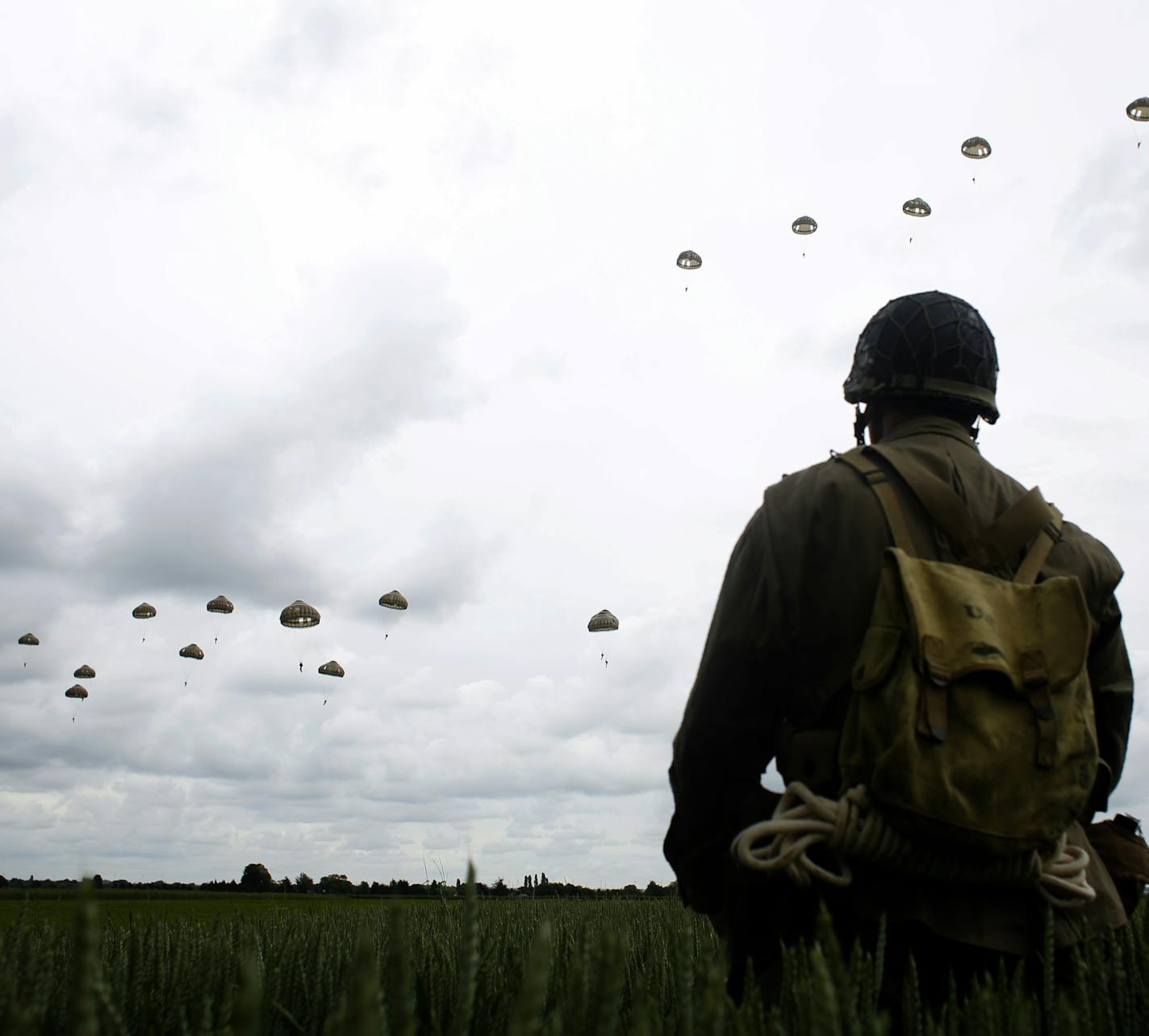 A WWII enthusiasts watches French and British parachutists jumping during a commemorative parachute jump over Sannerville, Normandy, Wednesday, June 5, 2019. Extensive commemorations are being held in the U.K. and France to honor the nearly 160,000 troops from Britain, the United States, Canada and other nations who landed in Normandy on June 6, 1944 in history's biggest amphibious invasion. (AP Photo/Thibault Camus)