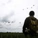 A WWII enthusiasts watches French and British parachutists jumping during a commemorative parachute jump over Sannerville, Normandy, Wednesday, June 5