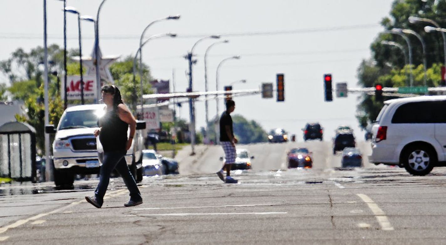 Two pedestrians take on traffic while crossing Robert Street near Butler Ave., July 26, 2011, in West St. Paul.