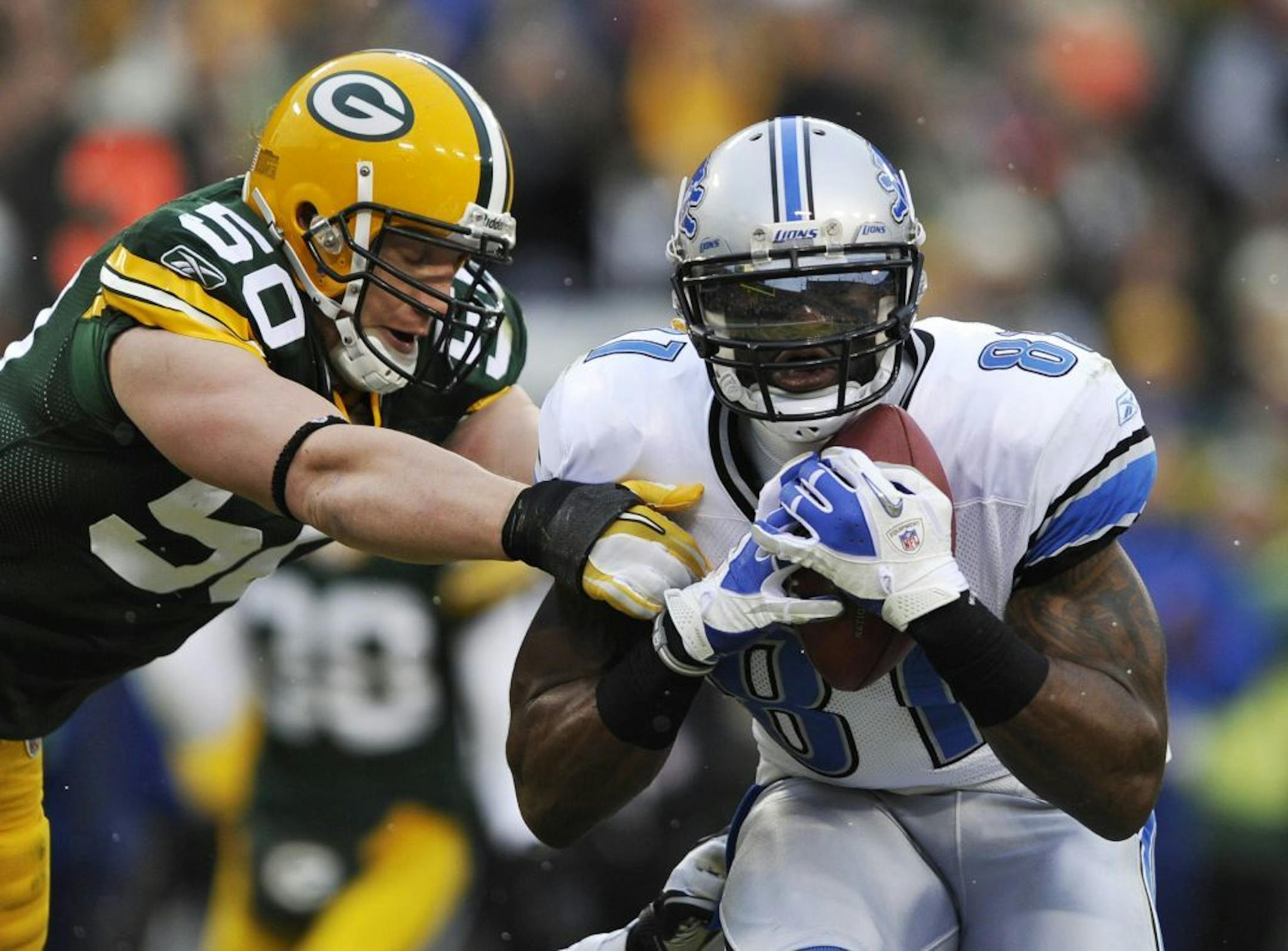 Detroit Lions' Calvin Johnson (81) catches a touchdown pass in front of Green Bay Packers' A.J. Hawk (50) during the first half of an NFL football game Sunday, Jan. 1, 2012, in Green Bay, Wis.