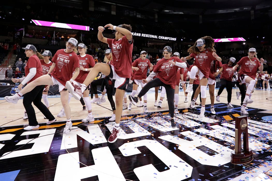 Stanford head coach Tara VanDerveer center, joins her players in a dance behind the regional trophy after winning the Spokane regional.