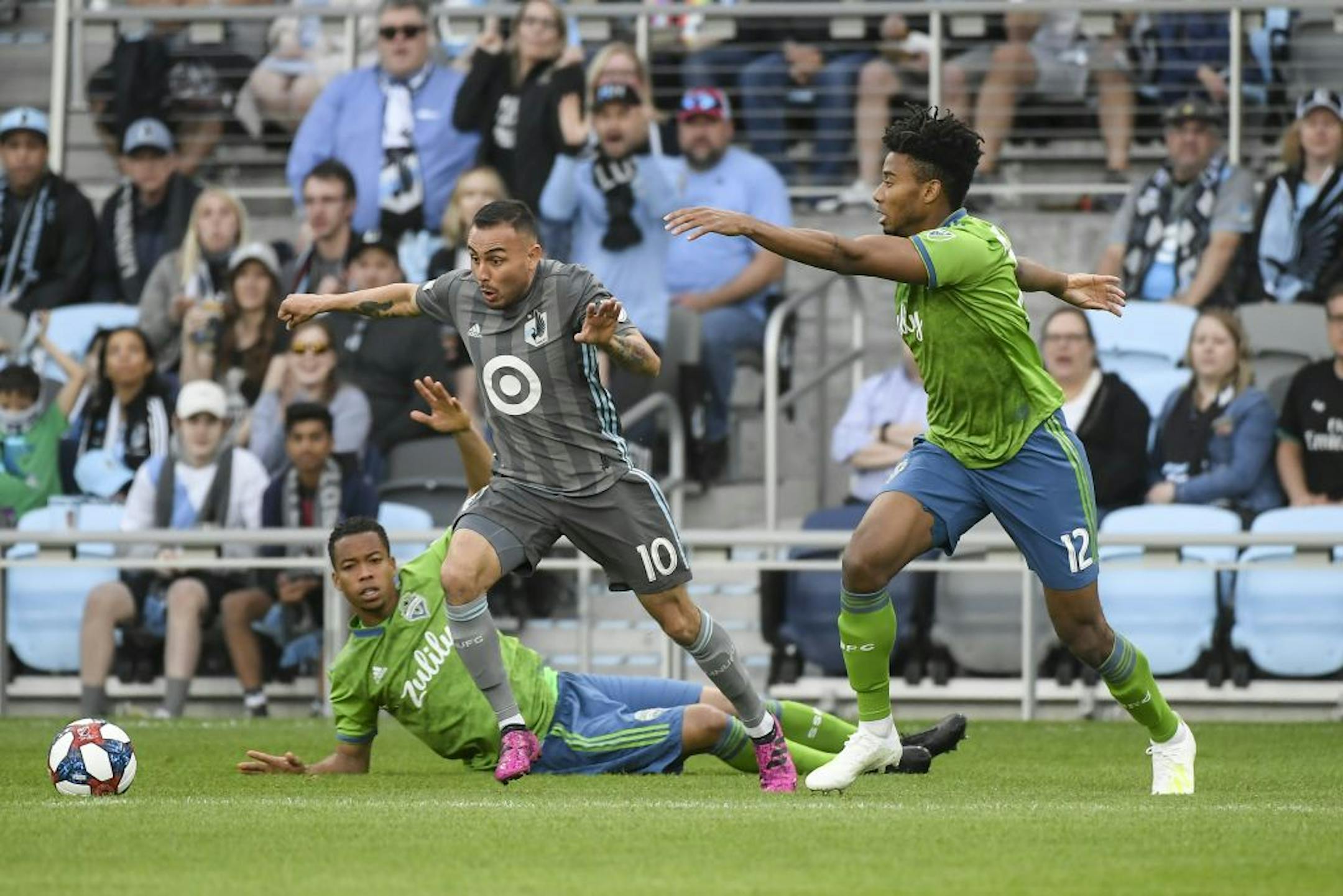 Minnesota United midfielder Miguel Ibarra (10) moved the ball against Seattle Sounders defender Saad Abdul-Salaam (12) as Seattle Sounders midfielder Jordy Delem (21) fell to the pitch in the first half.