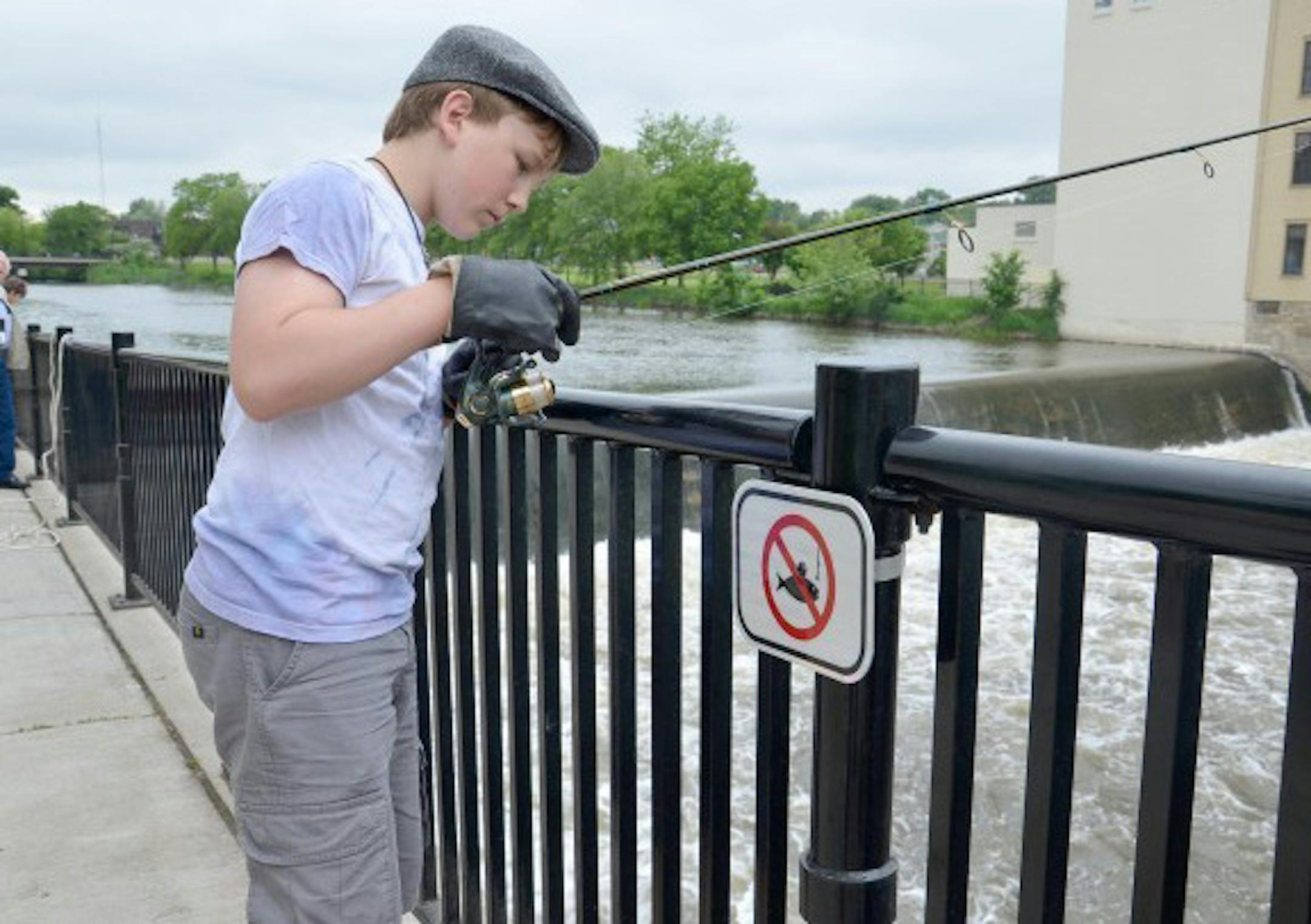 Cully Hauck, 13, of Northfields, tries his luck fishing at Bridge Square. Hauck said he and other boys in the area asked a city worker if they could keep fishing one day in June, 2013 which would be the last day they could. Photo by Jerry C. Smith/Northfield News