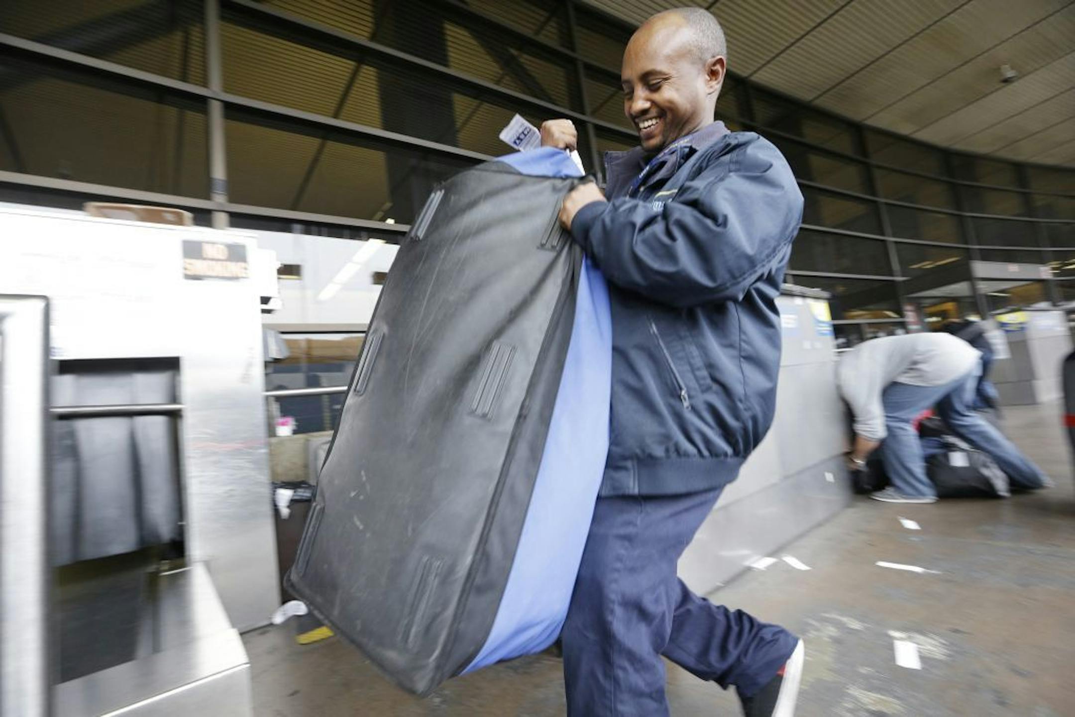 In this Tuesday, Oct. 22, 2013 photo, skycap Biniyam Yehuala hefts a traveler's bag at Seattle-Tacoma International Airport in SeaTac, Wash. There's a campaign underway to raise the minimum wage to $15 for the more than 6,300 jobs at Seattle's largest airport. If approved by voters on Nov. 5, the wage rate, as well as sick days and other benefits, would only apply to the city of SeaTac. The vote is one of the latest flashpoints in the national debate over the minimum wage after fast food workers