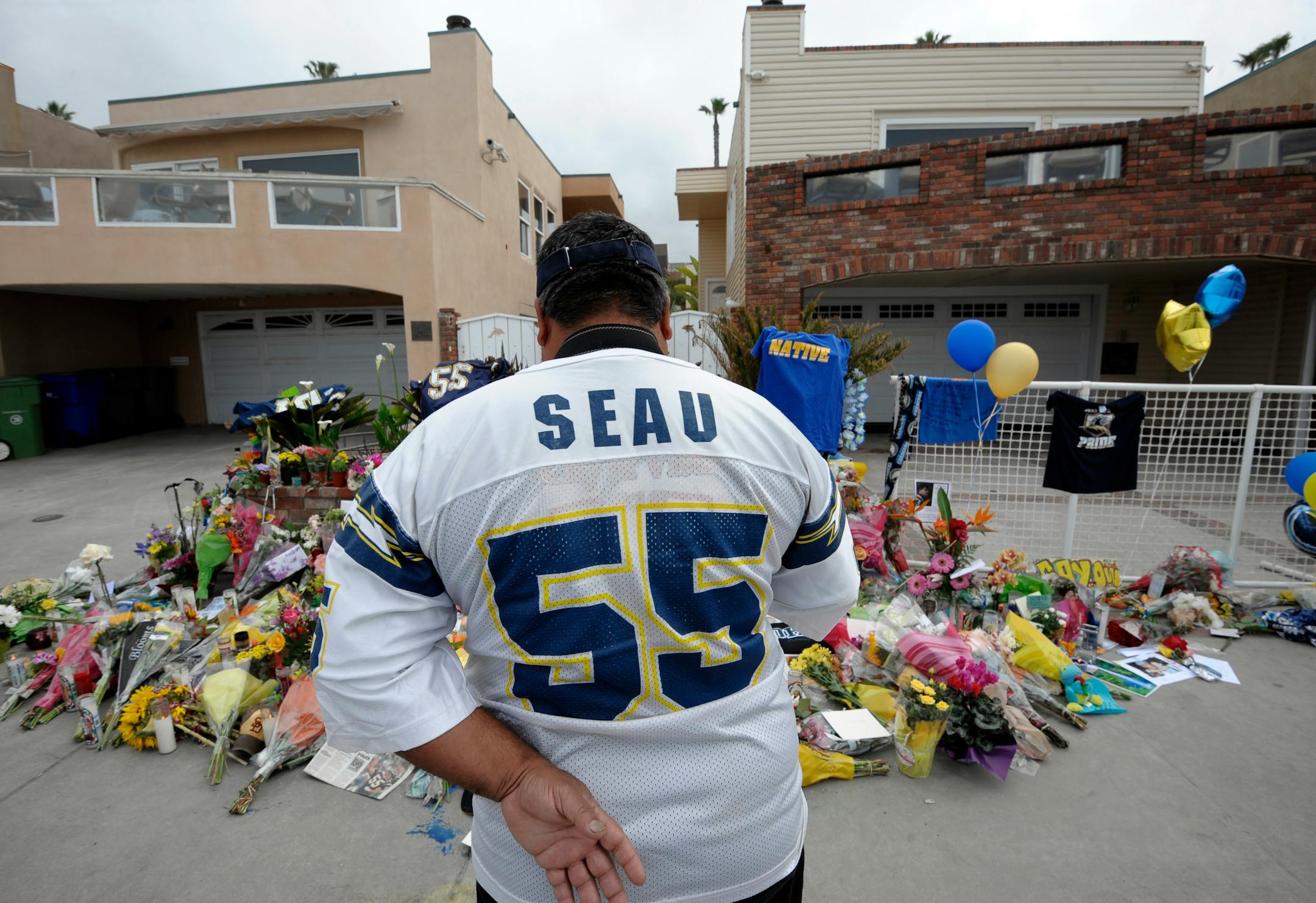 San Diego Chargers fan Jerry Lopez looks over a memorial set-up in the driveway of the house of former NFL star Junior Seau Thursday, May 3, 2012, in Oceanside, Calif. Seau's apparent suicide stunned an entire city and saddened former teammates who recalled the former NFL star's ferocious tackles and habit of calling everybody around him "Buddy." (AP Photo/Denis Poroy)