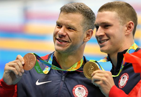 Minnesota&#xed;s David Plummer and teammate Ryan Murphy held up their Bronze and Gold medals in the 100 backstroke.