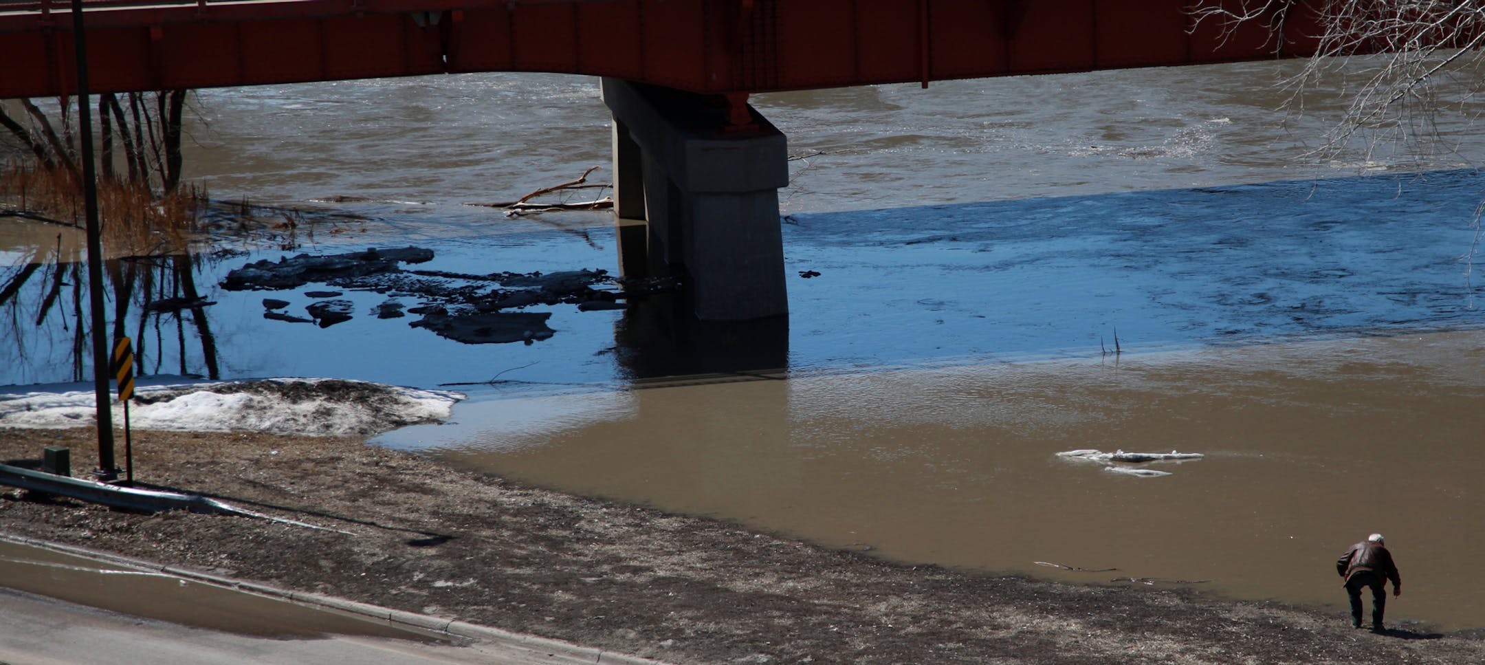 A man bends down to touch the Red River near Moorhead Center Mall on Friday, April 26, 2013. The river is projected to crest next week at the fifth highest level on record. In 2009, the river swelled to over 40-feet, and would have submerged the man in this photo. ] SHARI L. GROSS‚Ä¢ sgross@startribune.com