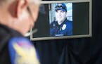 The image of Phoenix police officer David Glasser is displayed during a news conference as Phoenix Police PIO Vince Lewis, left, holds his head down o