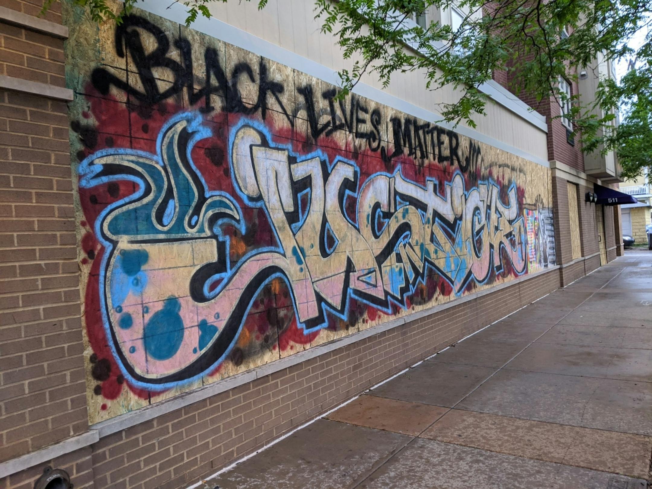 Anonymous artists paint tags demanding justice for George Floyd and Black Lives Matter on boarded-up windows of Midwest Market & Halaal-Meat (2000 Portland Ave. S., Mpls).