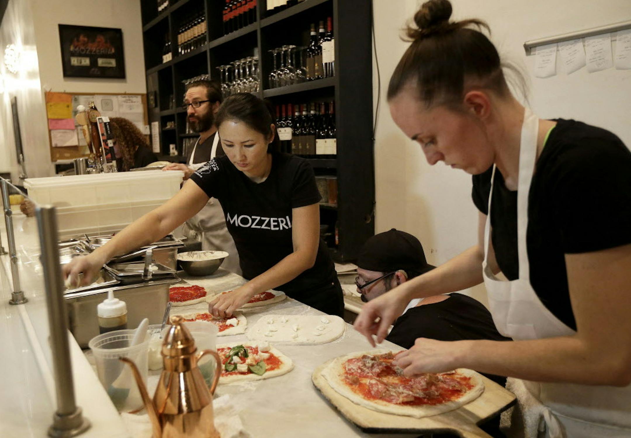 In this Nov. 5, 2015 photo, Mozzeria owner Melody Stein, left, and Sabrina Ferguson makes pizzas at the restaurant in San Francisco. Mozzeria owners Russ and Melody Stein as well as staff workers are deaf. (AP Photo/Jeff Chiu)