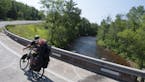 Ben Weaver rounding the corner over the Brule river on his 1,400 mile bike trip tour. Photo by Mike Riemer.