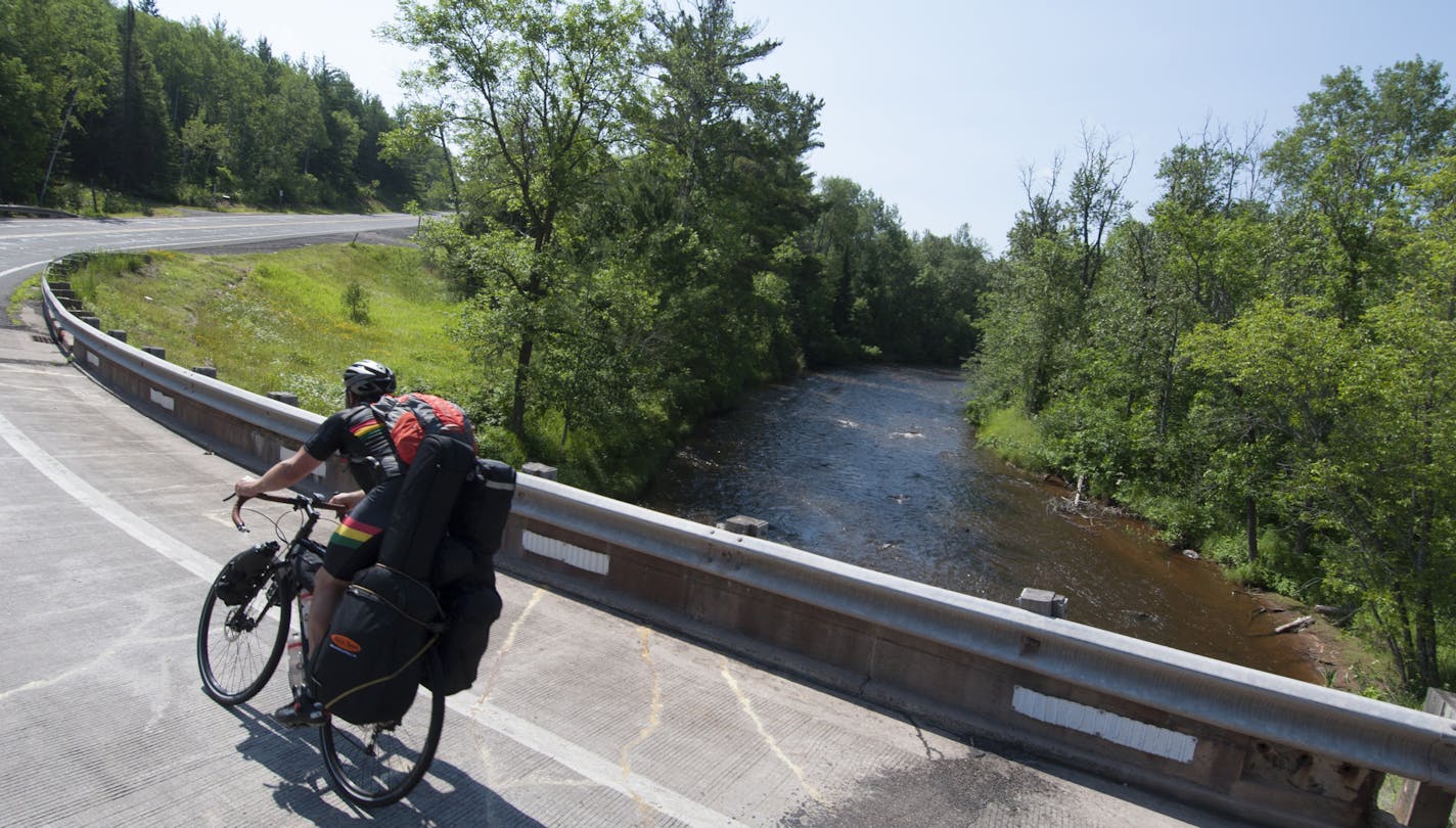 Ben Weaver rounding the corner over the Brule river on his 1,400 mile bike trip tour. Photo by Mike Riemer.