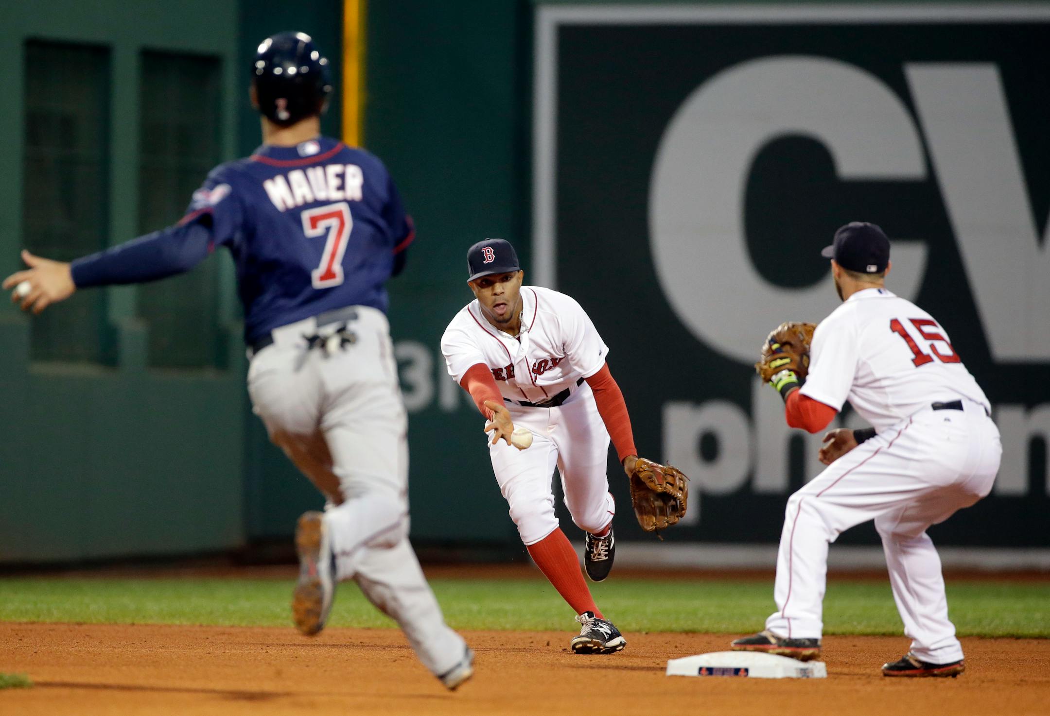 Boston Red Sox shortstop Xander Bogaerts flips the ball to second baseman Dustin Pedroia (15) to force Minnesota Twins' Joe Mauer (7) for the first half of a double play in the fourth inning of a baseball game Tuesday, June 2, 2015, in Boston. Kurt Suzuki was out at first. (AP Photo/Elise Amendola)