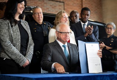 Gov. Tim Walz was flanked by politicians and police at the signing of a bill toughening penalties for “straw” purchases of guns at the St. Paul Po