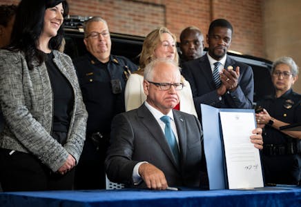 Minnesota Gov. Tim Walz signs a bill toughening penalties for “straw” purchases of guns at the St. Paul Police Department James S. Griffin Buildin